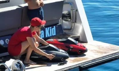 Sea Kid: 2台の水中スクーターのそばで船尾のプラットフォームにひざまずく赤い服の女性