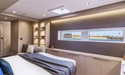 Verina Star: Cabine com cama de casal, manta cinza, longas janelas no casco e estantes embutidas