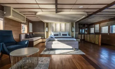 Maj Oceanic: Cabina spaziosa con letto matrimoniale, poltrona blu, tavolo rotondo e pavimento in legno