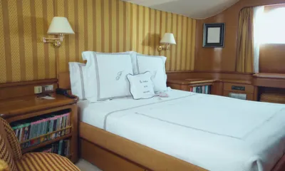 Freemont: Cabina con letto matrimoniale, cuscini ricamati, carta da parati a righe, lampade da parete e librerie