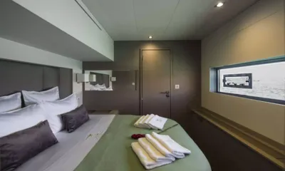 Lisa of the Seas: Cabin with green covered double bed, folded towels and a long hull window