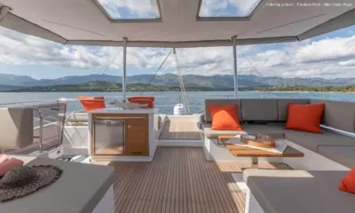 Looma: Schattiger Loungebereich auf dem oberen Deck mit orangefarbenen Kissen, Bar und Bergblick über die Bucht