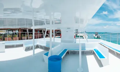 Party Cat: Pont ombragé avec banquette blanche et coussins bleus donnant sur la mer