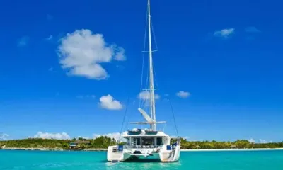 Amura II: Stern view of sailing catamaran anchored in turquoise water under a bright blue sky