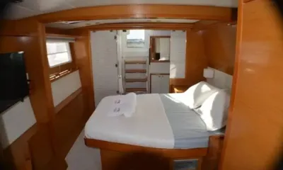 Amura II: Wood panelled cabin with white double bed, folded towels and steps leading up