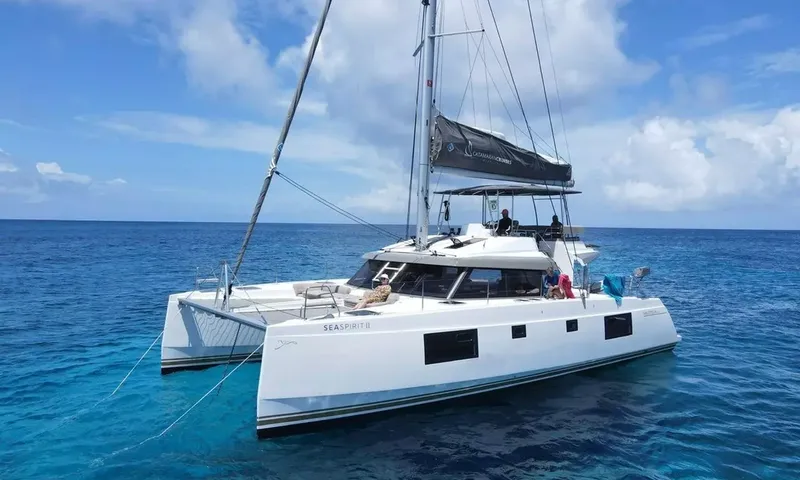 Sea Spirit 3: Catamarã de vela branco ancorado no mar azul com hóspedes relaxando no convés de proa