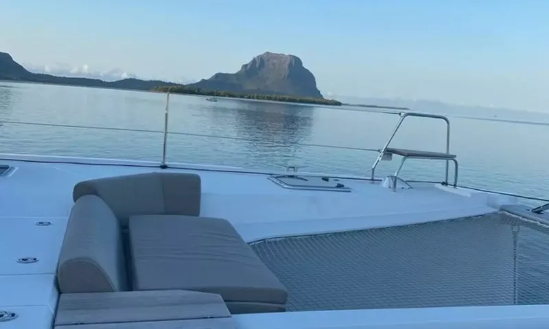 Sea Spirit 3: Almofadas do lounge de proa e rede trampolim voltadas para a água calma e uma montanha rochosa