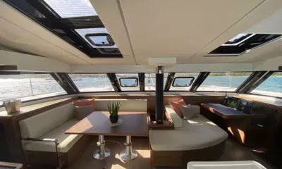 Sea Spirit 3: Salão luminoso com mesa de jantar, sofás creme, mesa de cartas e janelas panorâmicas
