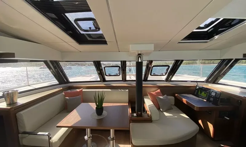 Sea Spirit 3: Salão luminoso com mesa de jantar, sofás creme, mesa de cartas e janelas panorâmicas