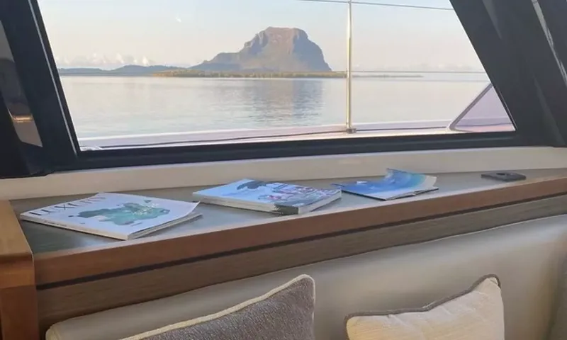 Sea Spirit 3: Revistas no peitoril de uma janela com vista para a água calma e uma montanha