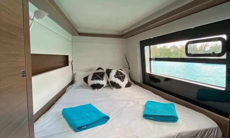 Sea Spirit 3: Cabine dupla com almofadas pretas e brancas, toalhas dobradas e janela com vista para o mar