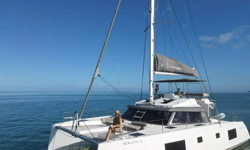 Sea Spirit 3: Catamarã ancorado sob céu limpo com uma mulher de chapéu sentada no convés