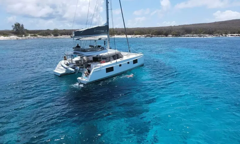 Sea Spirit 3: Catamarã ancorado em águas turquesa perto da costa com um nadador e um bote na popa