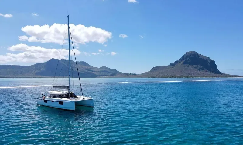 Sea Spirit 3: Catamarã ancorado no mar azul com montanhas e nuvens brancas ao fundo