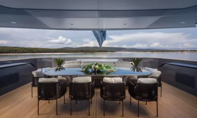 Panam: Mesa de jantar externa no deck de popa com cadeiras trançadas e arranjo floral de centro voltada para a água