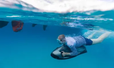 Play the Game: Persona che fa snorkeling mentre scivola sott'acqua tenendo uno scooter subacqueo