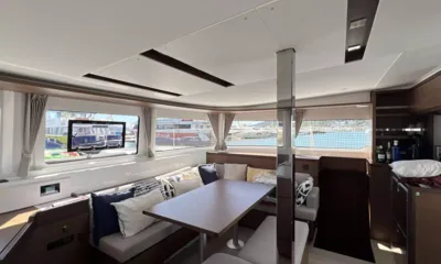 Saramimi: Bright saloon with cushioned corner sofa, wooden table and wide windows facing a marina
