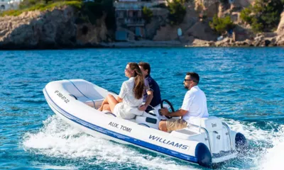 Tomi: Tre persone su un tender bianco sull'acqua blu vicino a una costa rocciosa