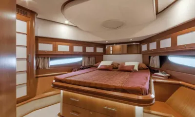 Mochi: Cabine com cama de casal com roupa de cama cor de ferrugem, armários de madeira e longas janelas no casco