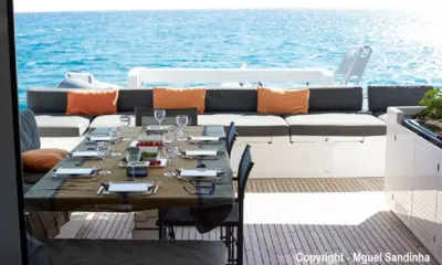 Breiz-Ile: Set outdoor dining table on the aft deck with glasses and cushioned bench facing the sea