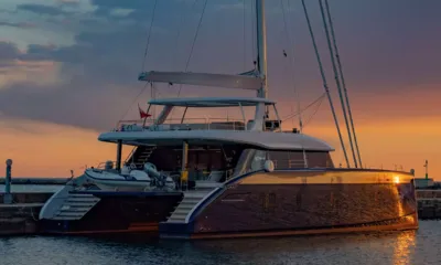 Fantastic Too: Catamarã a vela atracado em um muro do porto sob um céu colorido de pôr do sol