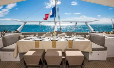 Magic Cat: Outdoor dining table set with glasses and plates on the aft deck facing the sea