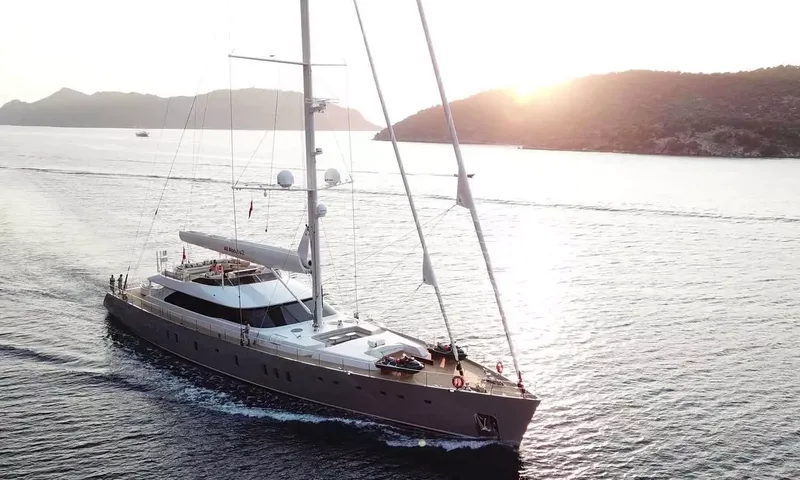 All About U 2: Sailing yacht cruising in a calm bay at sunset with wooded hills behind