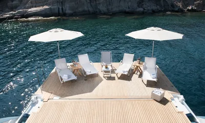 All About U 2: Lowered stern platform with sun loungers and two parasols over clear water near rocky shore