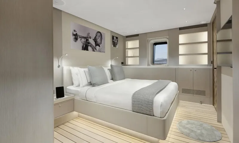 All About U 2: Light guest cabin with double bed, grey throw, porthole and black and white wall photos