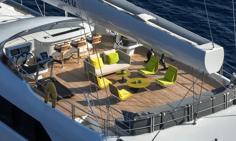 All About U 2: Elevated view of top deck lounge with yellow chairs, bar, helm and treadmill