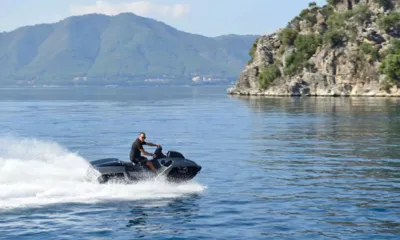 FX: 岩の崖の近くの穏やかな湾を黒いジェットスキーで走る男性