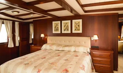 Halas 71: Cama de casal com cabeceira estofada, abajures e gravuras de pássaros emolduradas em uma cabine de madeira