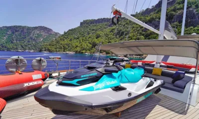 Queen of Makri: Jet ski no convés ao lado de boias rebocáveis e uma lounge sombreada, colinas arborizadas ao fundo