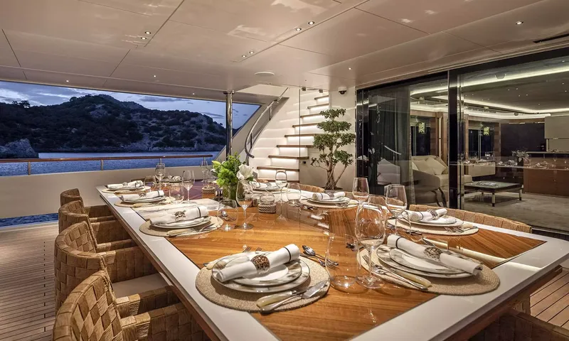 Sunrise: Outdoor dining table set for dinner at dusk beside glass doors and stairs