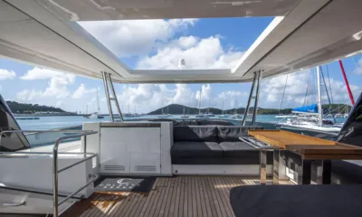 Colette: Lounge do deck superior sob um teto aberto, com sofá, mesa e vista de veleiros ancorados