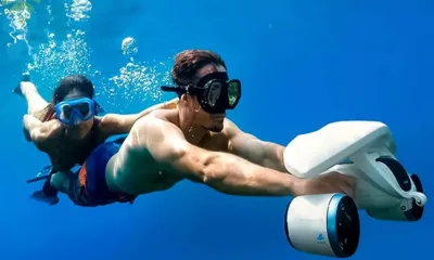 Tru North: Dois mergulhadores de snorkel deslizando debaixo d'água, um segurando um scooter subaquático branco