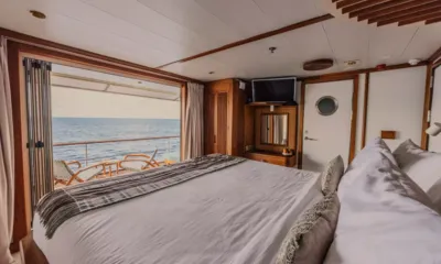 Kudanil Explorer: Double bed facing open doors to a private balcony with chairs and sea view