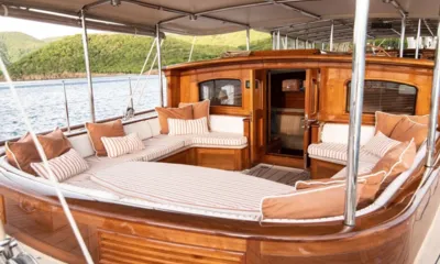 Athos I: Lounge de deck sombreado com almofadas listradas ao redor de uma casaria de madeira