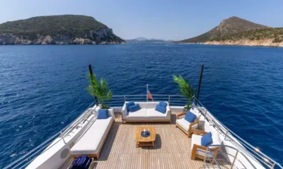 Ocean View: Lounge aberto no deck com sofás, almofadas azuis e mesa de centro com vista para uma baía e colinas