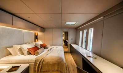 Viva La Vida I: Cabine com cama de casal, almofadas laranja, longa bancada de penteadeira e janelas altas no casco