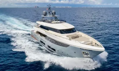 Cofina: Yacht a motore in navigazione che lascia una scia bianca, skyline della città all'orizzonte