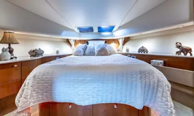 Elegant Lady: Cabina di prua con letto matrimoniale con trapunta bianca, mobili in legno, lampade e osteriggi sopra