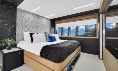 Gypsea: Cabine dupla com manta preta, parede de cabeceira texturizada e janela no casco com vigia