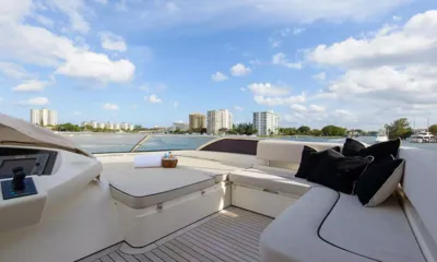 Catalana: Prendisole del flybridge e sedute bianche curve con cuscini neri sotto un cielo soleggiato