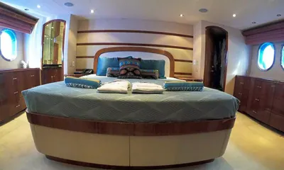 TopShelf: Camarote con cama doble grande, almohadas azules, cómodas de madera y portillas redondas