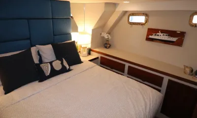 Sea Princess: Double bed with blue padded headboard, shell cushions, wooden drawers and brass portholes