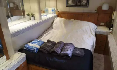 Sheer Delight: Cabine com cama de casal, toalhas cinza dobradas, gavetas de madeira e prateleira espelhada com plantas