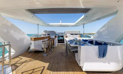 4 Play: Flybridge com banquetas de bar, mesa de jantar posta em azul e hardtop aberto sob um céu limpo