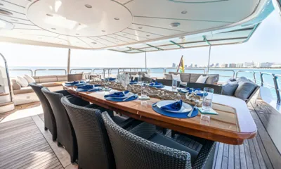 Arthur's Way: Mesa de jantar externa posta com guardanapos azuis e cadeiras de vime sob uma cobertura do deck