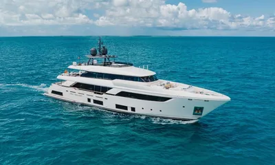 Eros: Iate branco navegando em um mar turquesa sob um céu nublado, visto de cima em ângulo